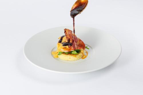 a plate with a sandwich with bacon and a spoon at Suvretta House in St. Moritz
