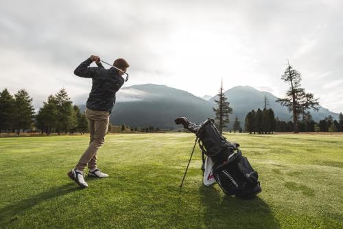 a man swinging a golf club on a golf course at Suvretta House in St. Moritz