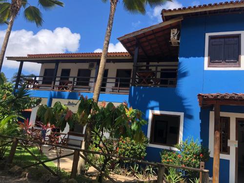 a blue building with palm trees in front of it at Pousada Ponta da Baleia in Barra Grande