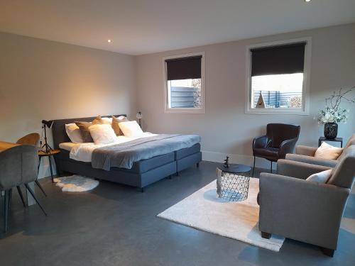 um quarto com uma cama, um sofá e cadeiras em B&B tRust em Barneveld