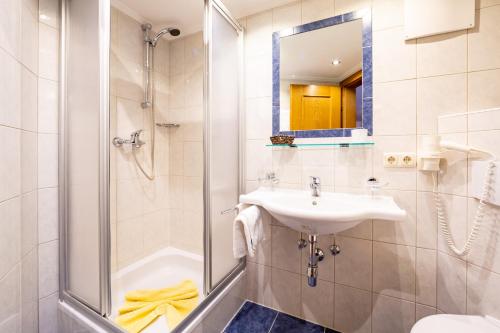 a bathroom with a shower and a sink and a mirror at Hotel Garni Tyola in Ischgl