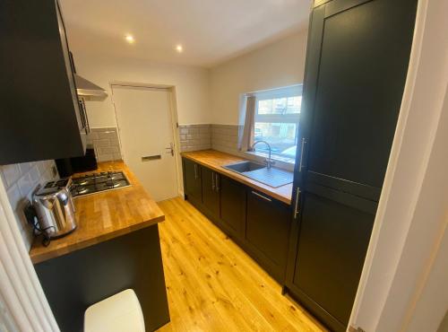 eine Küche mit einem schwarzen Kühlschrank und Holzböden in der Unterkunft Spacious and bright 1 - bedroom rental unit in Ilkley