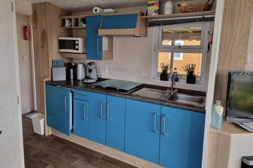 a kitchen with blue cabinets and a sink at CS 9 - Vakantiepark Callassande in Callantsoog