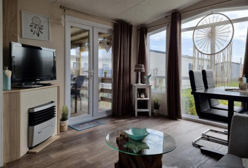 a living room with a tv and a glass table at CS 9 - Vakantiepark Callassande in Callantsoog