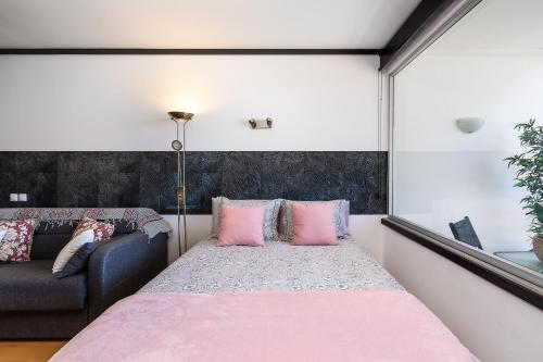 a bedroom with a bed with pink pillows and a couch at Apartamento Portugal in Quarteira