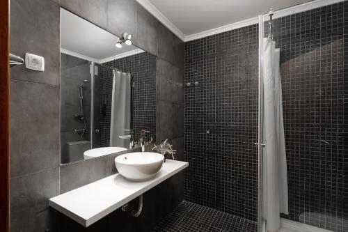 a black and white bathroom with a sink and a shower at Apartamento Portugal in Quarteira