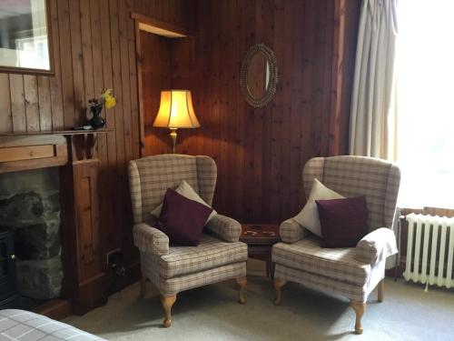 a living room with two chairs and a table and a lamp at Westward Bed and Breakfast in Cannich