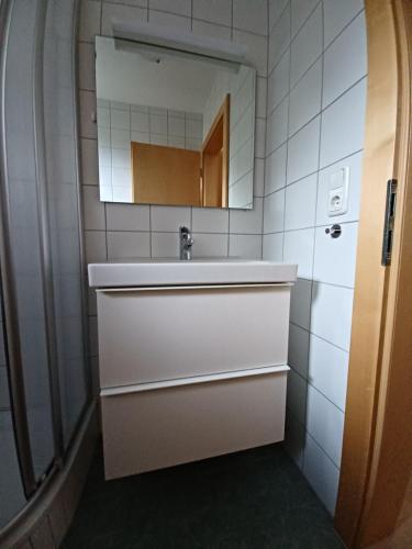 Baño blanco con lavabo y espejo en Ferienapartment Prantner, en Grins
