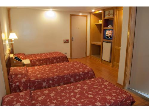 a hotel room with two beds and a television at King Hotel in Sao Paulo