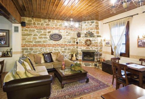 a living room with a couch and a stone fireplace at Villa Kastanodasos in Emporio