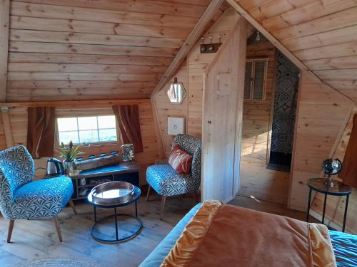 Habitación con cama y sillas en una cabaña en A l'orée du Cèdre en Pouzauges