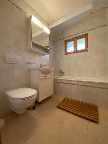 La salle de bains est pourvue de toilettes, d'un lavabo et d'une baignoire. dans l'établissement Chalet Marguerite - bel appartement 3 chambres avec feu ouvert, vue imprenable, dans un chalet à taille humaine de 6 unités, à Val dʼIlliez