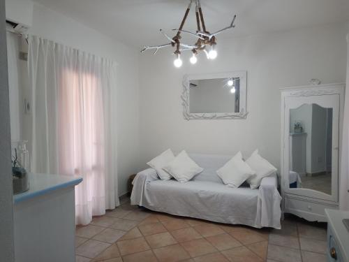a white room with a bed and a mirror at Appartamento Piano Terra Residence Geranium Beach in San Teodoro