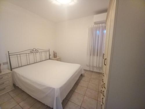 um quarto branco com uma cama e uma janela em Appartamento Piano Terra Residence Geranium Beach em San Teodoro