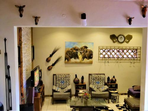 a living room with two chairs and a painting of elephants at Lake Victoria Country Home in Entebbe