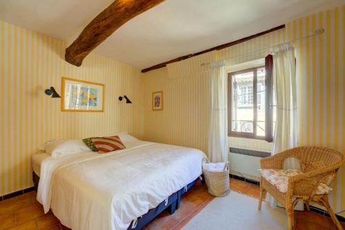 罗克布吕讷-卡普马丹Ancienne Mairie Vieux Village Roquebrune 3 bedroom apartment的一间卧室，里面有一张床、一把椅子和一扇窗户