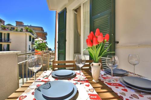 a table with plates and wine glasses on a balcony at Jolly Roger Riomaggiore in Riomaggiore