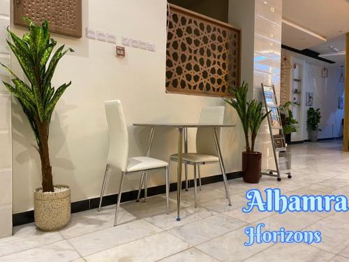 a table and chairs in a room with plants at Alhamra Horizons in Al Ḩamrāʼ