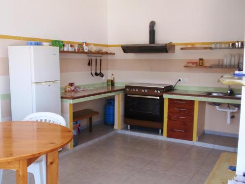 a kitchen with a white refrigerator and a table at Zena Star in Tarrafal