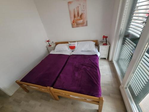 a bed in a room with a purple blanket at 2 bedroom apartment on the coast of the Adriatic! Watermelon Marina in Marina