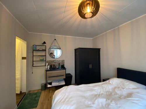 1 dormitorio con 1 cama blanca y 1 lámpara en Holiday aan de Kust, en Rijnsburg