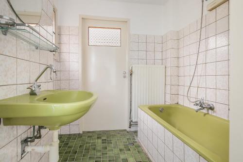 een badkamer met een groene wastafel en een bad bij Voorstraat-Havenzicht 1ste in Dordrecht