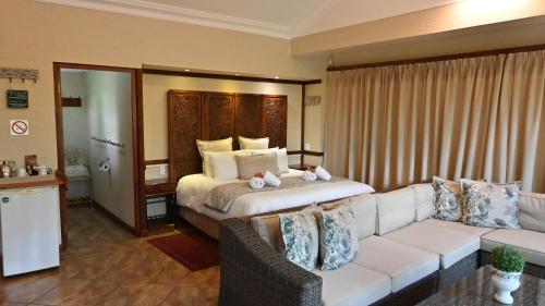 a hotel room with a bed and a couch at LUXURY EN-SUITE ROOM WITH LOUNGE @ 4 STAR GUEST HOUSE in Middelburg