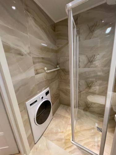 La salle de bains est pourvue d'une douche et d'un lave-linge. dans l'établissement Livinga Lovely 1-bedroom apartment, à Mažeikiai