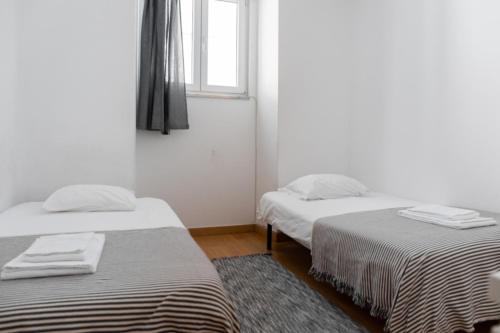 2 letti in una camera con finestra e tappeto di Entrecampos - Two bedroom apartment with Terrace a Lisbona