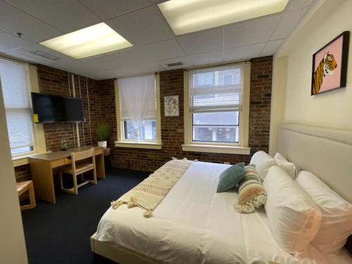 a bedroom with a bed and a desk and windows at Michie House in College Hill in Providence