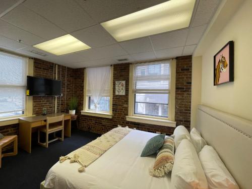 a bedroom with a bed and a desk and windows at Michie House in College Hill in Providence