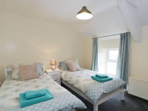 a bedroom with two twin beds and a window at Ty Rhos, Farm Stay, sleeps 4, Rhoshirwaun 2 miles from Aberdaron in Aberdaron