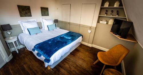 a bedroom with a bed and a tv and a chair at B&B Maison Rabelais in De Haan