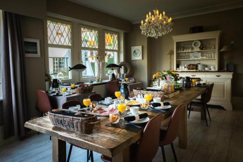 a dining room with a table with food and drinks on it at B&B Maison Rabelais in De Haan
