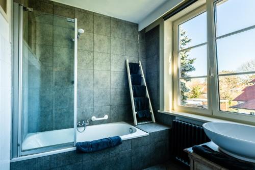 a bathroom with a tub and a sink at B&B Maison Rabelais in De Haan