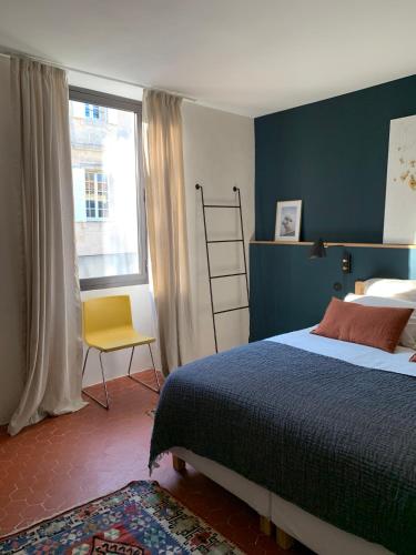 une chambre avec un lit, une fenêtre et une chaise dans l'établissement La Blanchisserie, à Maussane-les-Alpilles
