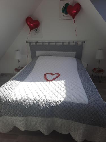 a bed with two red heart balloons on it at Au bonheur des hirondelles in Kirrwiller
