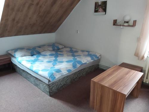 a small bedroom with a bed and a wooden table at Hotel Hubert in Hřensko
