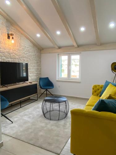 ein Wohnzimmer mit einem gelben Sofa und einem TV in der Unterkunft Citadela in Primošten