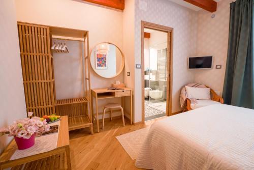 een slaapkamer met een bed, een bureau en een spiegel bij Sa Domo e Giuanne e Giuanna in Bosa