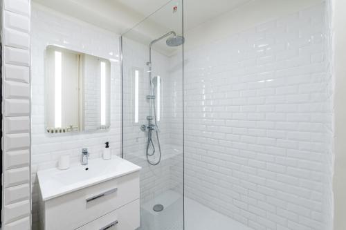 La salle de bains blanche est pourvue d'un lavabo et d'une douche. dans l'établissement Gare St Charles- Superbe appartement avec 3 chambres, à Marseille