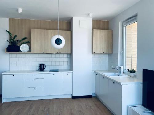 a kitchen with white cabinets and a sink at Apartament Błękitna Zatoka z Sauną in Puck