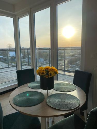 a table with three green plates and a vase with flowers at Apartament Błękitna Zatoka z Sauną in Puck