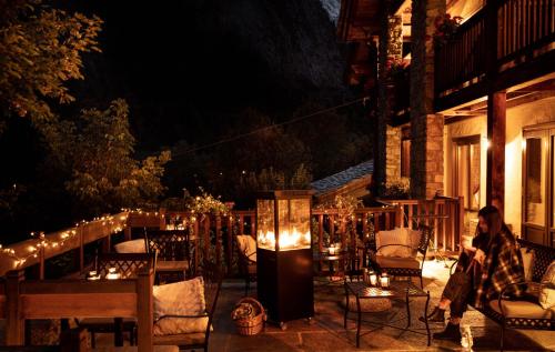 a woman sitting on a chair on a patio at night at Auberge de La Maison in Courmayeur