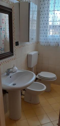 a bathroom with a sink and a toilet and a window at Via Pioppa 24 in Ferrara