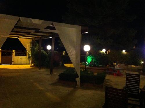 a lit up pavilion at night with a green light at Chris Studios & Apartments in Lechaio