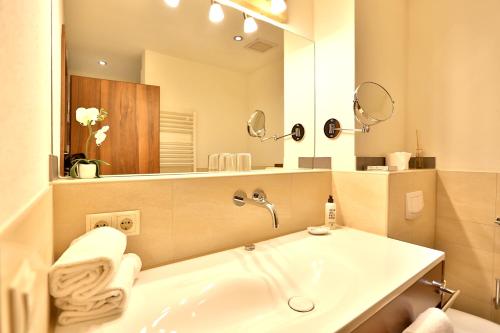 a bathroom with a sink and a large mirror at Seehotel Hartung & Ferienappartements in Füssen
