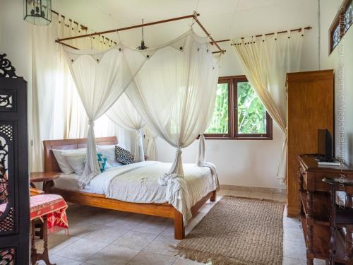 a bedroom with a canopy bed with white curtains at Villa Medori - Private Pool Seminyak in Seminyak