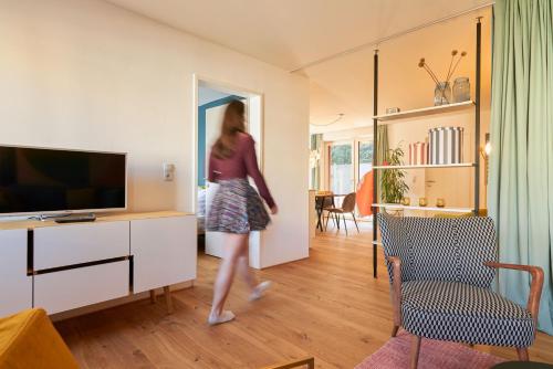 Una donna sta camminando in un soggiorno di Rotes Haus Bregenz Pop-Up Wohnung a Bregenz