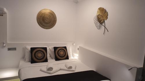 a white bedroom with a bed with gold and black pillows at Mykonos Double Luxury Mini Suites-With External Hot spa Adults only in Ano Mera